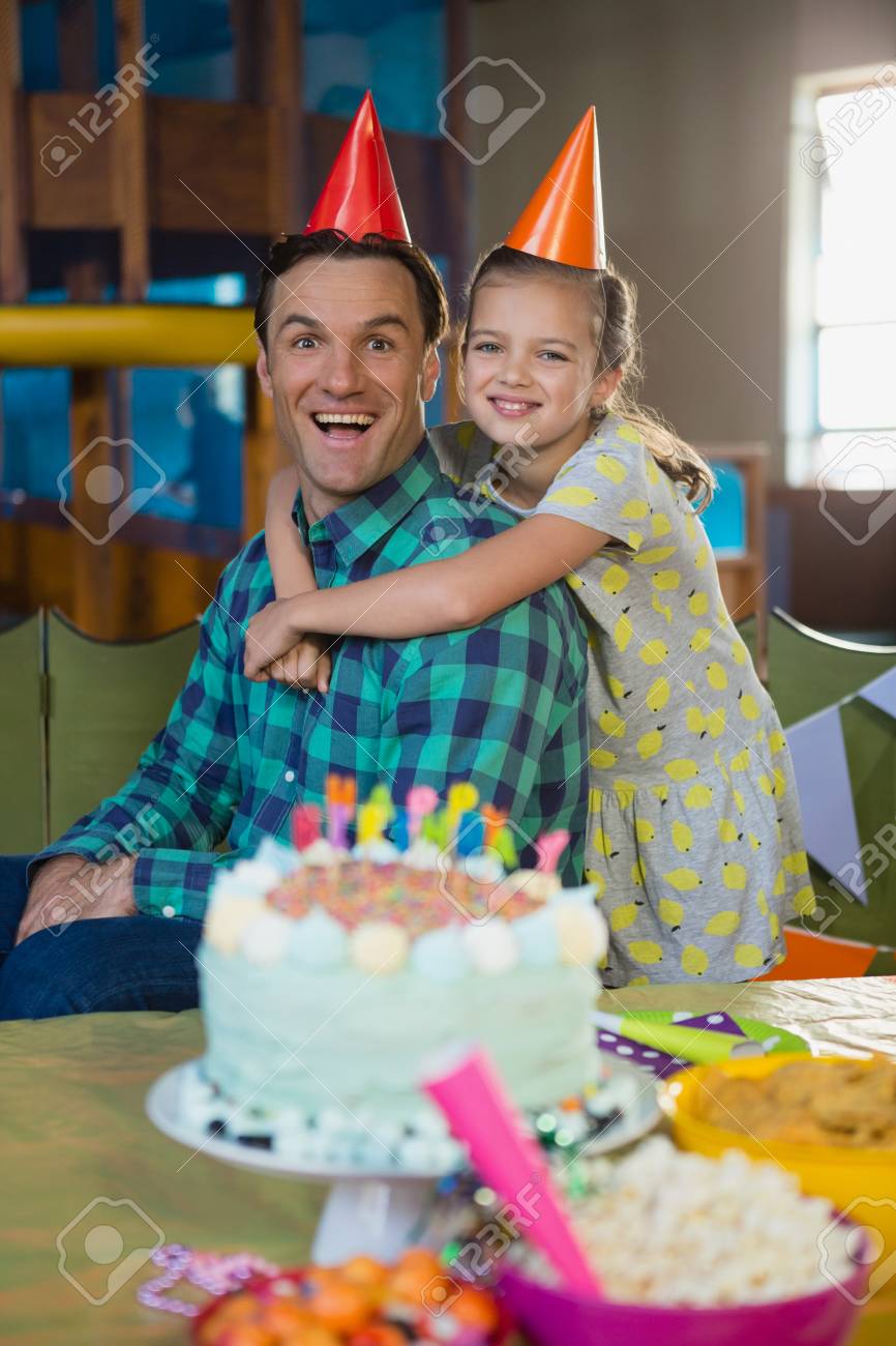 Padre e hija sonrientes con un pastel de cumpleaños
