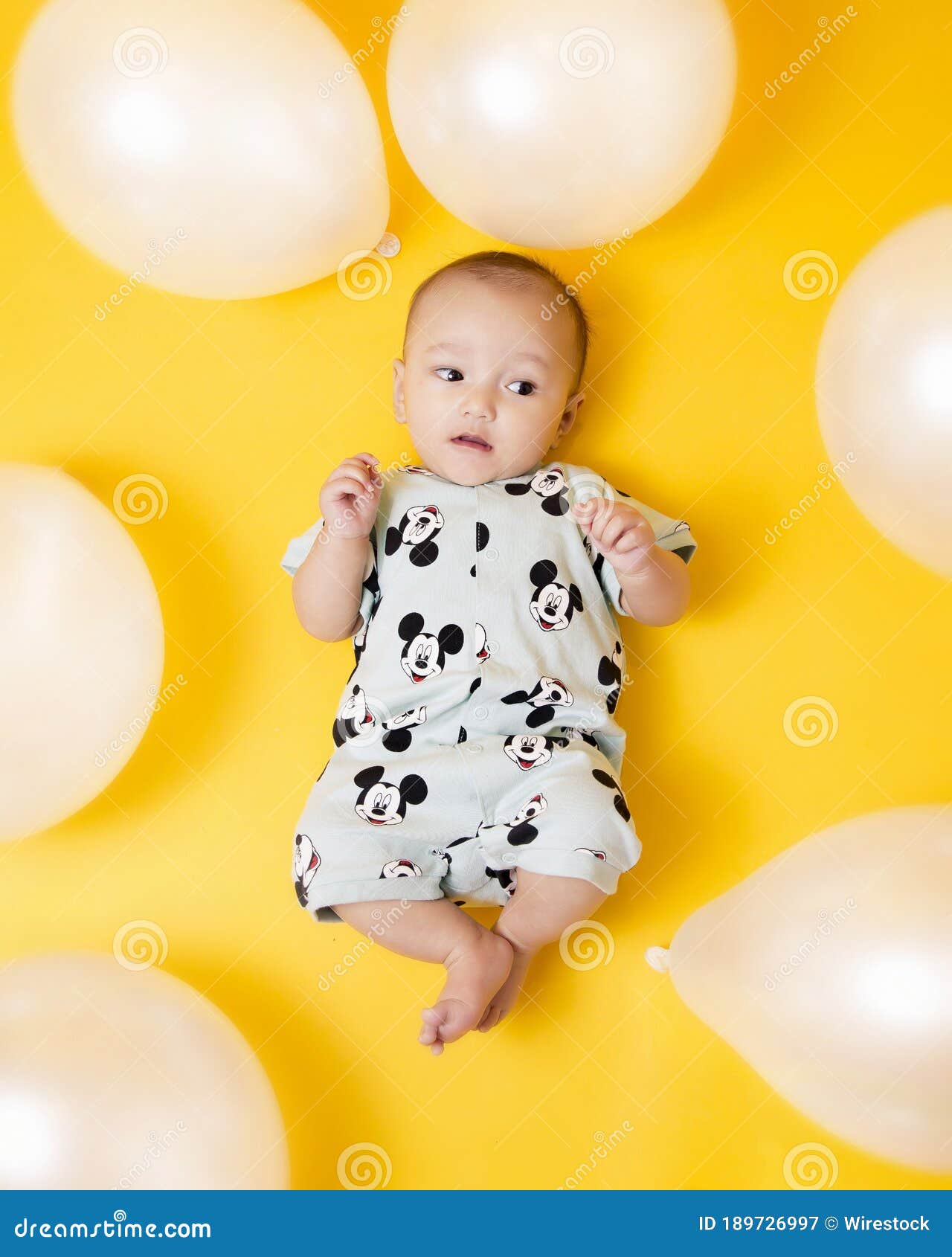 Happy baby surrounded by colorful balloons